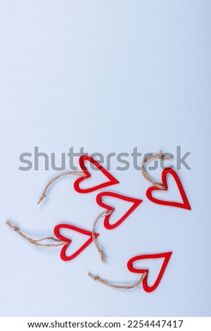 Valentines day background. Vertical view of red wooden hearts tied with string on a light blue background.