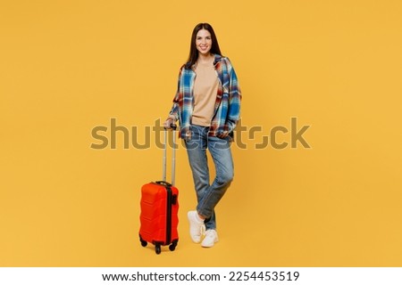 Full body smiling traveler fun woman wear casual clothes hold valise isolated on plain yellow background studio. Tourist travel abroad in free spare time rest getaway. Air flight trip journey concept