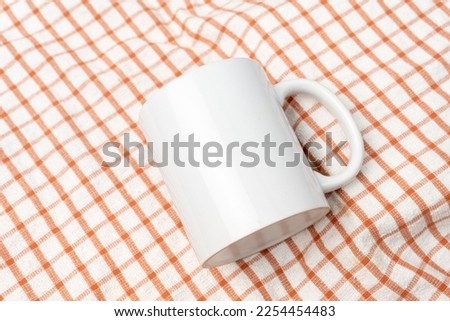 A white blank coffee mug on the top of a hand cloth with clean and simple looks, coffee mug mockup image
