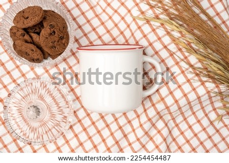 A white blank enamel mug on the top of a hand cloth decorated with simple stuff around it, enamel mug mockup image