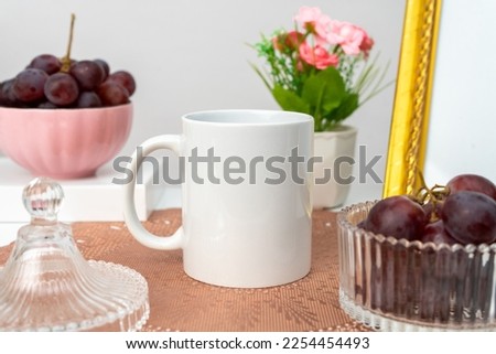 A white blank coffee mug on the top of a rounded mat decorated with simple stuff around it, coffee mug mockup image