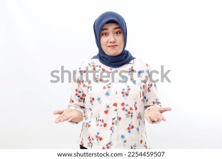 Happy asian veiled woman standing while presenting something on her hands. Isolated on white background