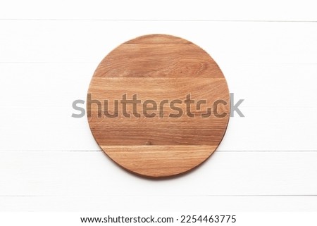 Empty round wooden cutting board on white table. Round cutting board or serving tray mockup. Flat lay, top view.