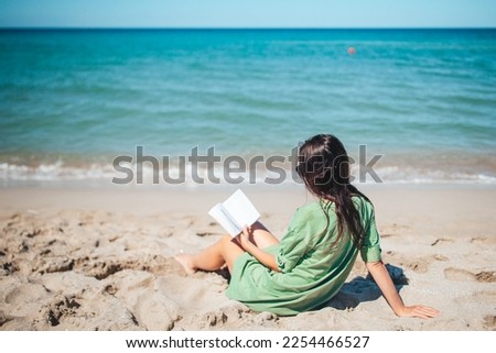 Young woman reading book during tropical white beach Royalty-Free Stock Photo #2254466527