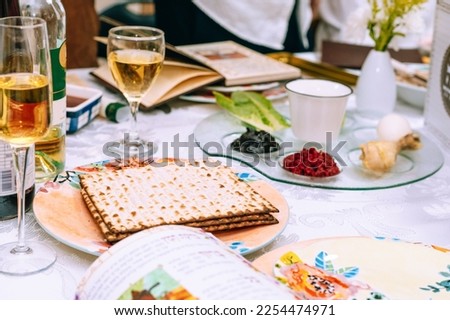 Passover table setting with a traditional Passover seder plate with symbolic meal, matzah and Haggadah. Table served for Passover Seder - Pesach. Royalty-Free Stock Photo #2254474971