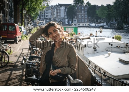 Portrait of smiling woman standing against canal in city