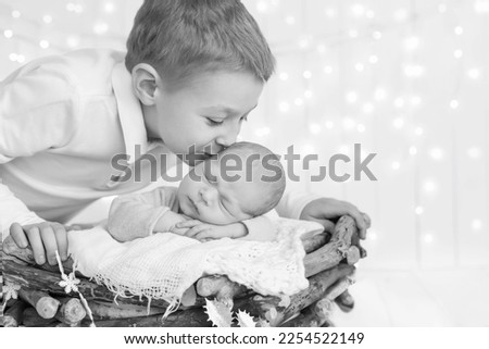 black and white photo older brother lies, hugs, hugs and holds the hand of his newborn younger brother