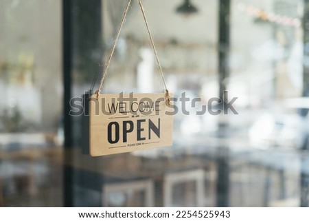 Open wooden sign broad through the glass of store window