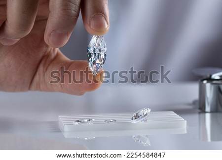 Close up of a marquise cut diamond in the hand of an expert evaluating diamonds. Royalty-Free Stock Photo #2254584847