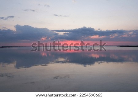 Sunset clouds reflecting on lake landscape photo. Beautiful nature scenery photography with skyline on background. Idyllic scene. High quality picture for wallpaper, travel blog, magazine, article