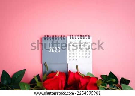 The concept for Valentine's day on 14th February 2023. Mark heart on 14th calendar of February with red rose flower on the red background on a desk, Copy space, Selective focus, blurred background