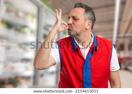 Satisfied worker making okay gesture with fingers on mouth as very good concept