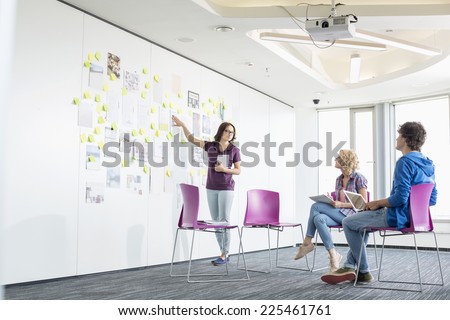 Businesswoman giving presentation to colleagues in creative office space