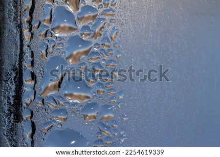 Macro abstract texture background of water droplets and ice forming on an interior glass window pane, with natural designs