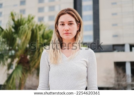Close up portrait of blonde caucasian young woman looking serious at camera. Pretty teenage girl staring front with sad attitude. High quality 4k footage Royalty-Free Stock Photo #2254620361