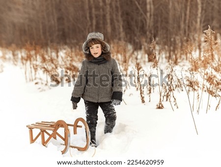 Happy little boy playing snowballs in winter park. Winter forest in the background. High quality photo
