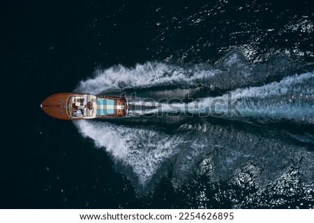 luxury wooden big motorboat with people fast moving on dark water top view Royalty-Free Stock Photo #2254626895