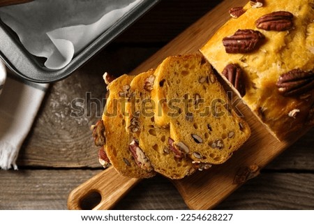 Cut pumpkin bread with pecan nuts on wooden table, flat lay