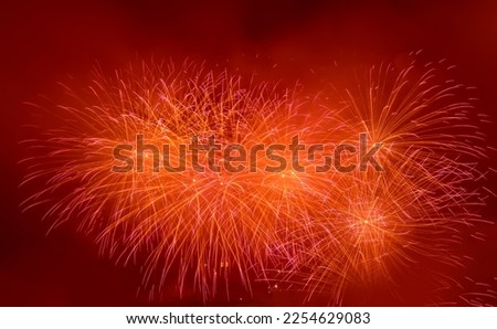 Beautiful red fireworks display lights up the sky with dazzling display during New Year celebration. Abstract colored fireworks background with copy space. Celebration and anniversary concept