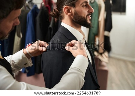 Experienced clothier altering suit of male client Royalty-Free Stock Photo #2254631789