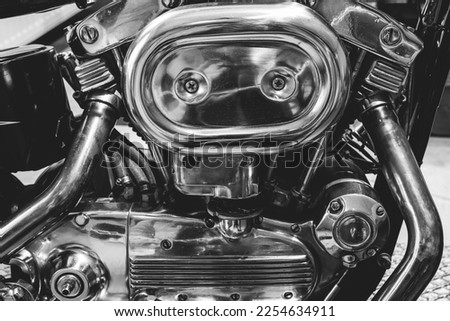 Black and white picture of fragment of v-twin engine in old-fashioned chopper. Chrome motor housing.