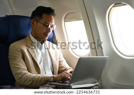 Image of businessman passenger sitting comfortable seat working with laptop on airplane cabin
