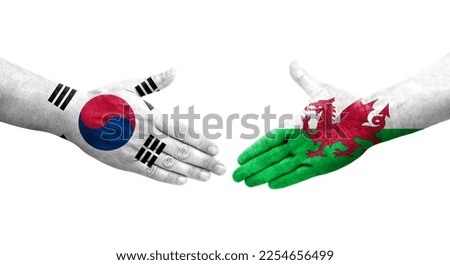 Handshake between South Korea and Wales flags painted on hands, isolated transparent image.