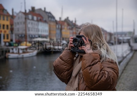 A tourist on holiday in Copenhagen takes pictures with her camera in Nyhavn