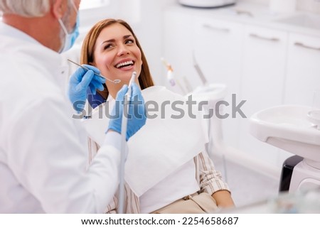 Dentist fixing patient's tooth at dental clinic using dental drill and angled mirror Royalty-Free Stock Photo #2254658687