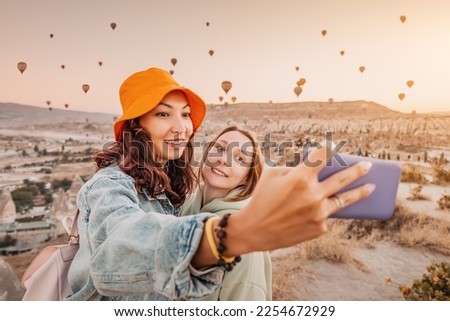 Two happy girl friends taking selfie photos on smartphone in Cappadocia, Turkey. Travel and social media concept