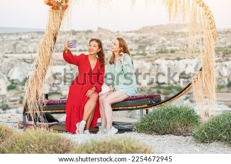Girls friends travel bloggers take selfie photos on a smartphone on an observation deck in Cappadocia in Turkey