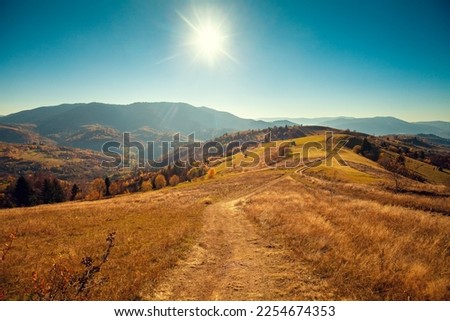 Mountain landscape on a sunny day in autumn. View of the mountain slopes and dirt road. Beautiful nature landscape. Carpathian mountains. Ukraine Royalty-Free Stock Photo #2254674353