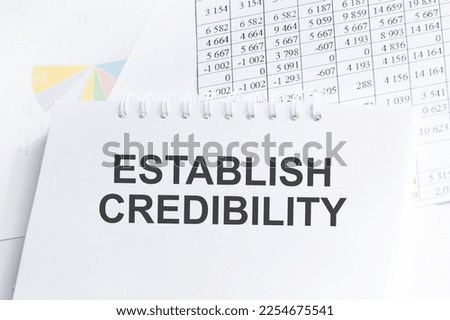 ESTABLISH CREDIBILITY. text on an open notebook on a wooden background near glasses