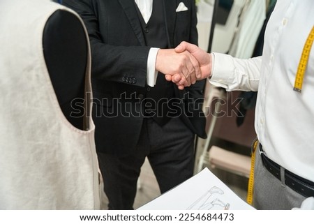 Gentleman exchanging handshake with fashion designer indoors