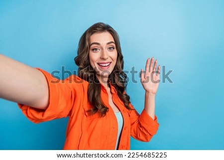 Photo of adorable pretty woman dressed orange jacket waving arm palm recording self video isolated blue color background