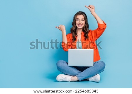Full size photo of pretty girl point empty space laptop apple macbook samsung dressed stylish orange look isolated on blue color background