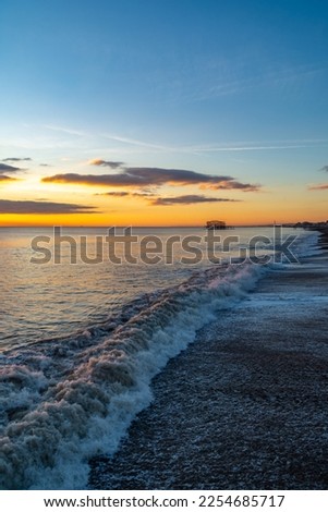 Brighton, UK - December 1st 2022: Wave on Brighton Beach with the remains of the West Pier in the background.