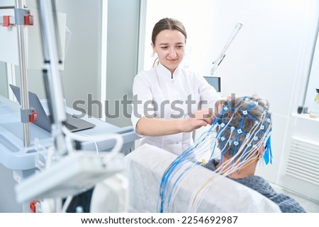 Woman diagnostician attaches sensors to the patient head