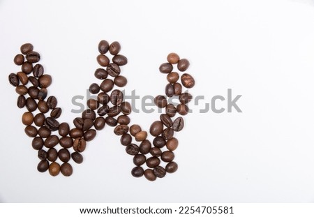 W is a capital letter of the English alphabet made up of natural roasted coffee beans that lie on a white background. Plenty of space to put text or pictures, top view and studio photography.