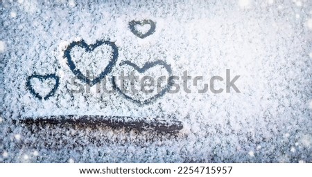 Four hearts (symbol of love) hand drawing (painted) on snow on the glass above windshield wiper of a car. Valentine's Day, love, honeymoon, winter, transport concept. Copy space. Selective focus.