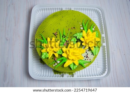 Round big cake of green color with cream and yellow flowers. Jelly confectionery