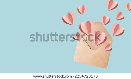 Love letter envelope with paper craft hearts - flat lay on blue valentines or anniversary background with copy space.
