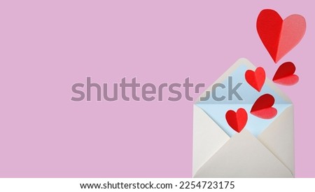 Love letter envelope with paper craft hearts - flat lay on pink valentines or anniversary background with copy space.