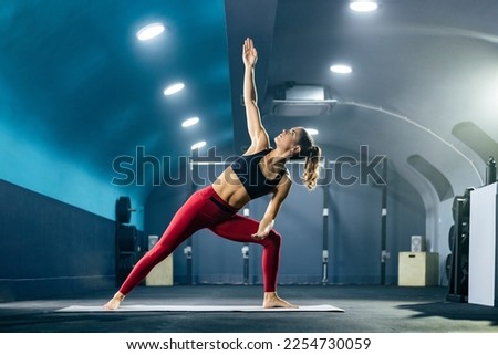 Young fit woman in sportswear doing yoga at gym in extended side angle pose. Royalty-Free Stock Photo #2254730059