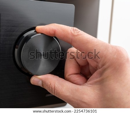 Hand turning the volume knob of an amplifier up to the maximum, Concept for noisy environment or hearing problems Royalty-Free Stock Photo #2254736101