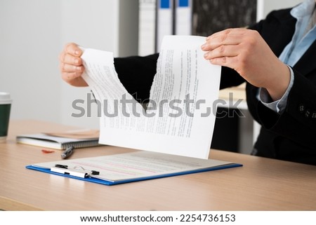 Close-up of the hands of a businesswoman tearing up the signed contract document sitting at a desk in the office Royalty-Free Stock Photo #2254736153