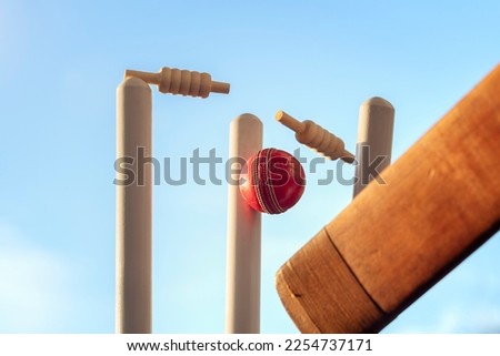 Cricket bat and cricket ball hitting wicket stumps knocking bails out, how's that! Royalty-Free Stock Photo #2254737171