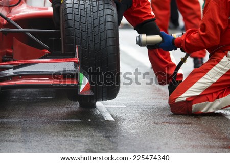 Professional racing team at work during a pitstop of a race car in the pitslane during a car race. Royalty-Free Stock Photo #225474340