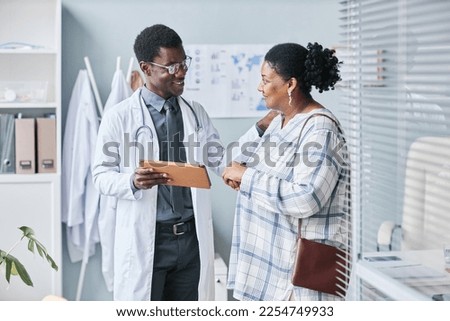Waist up portrait of young African American doctor consulting female patient using digital tablet in clinic setting Royalty-Free Stock Photo #2254749933