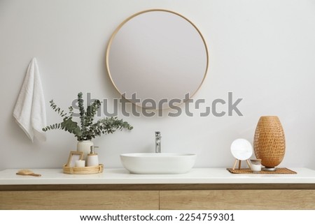 Stylish mirror, eucalyptus branches and vessel sink in modern bathroom. Interior design Royalty-Free Stock Photo #2254759301